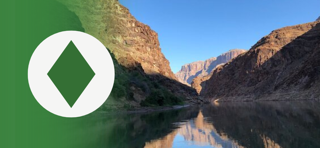 Scenic view of a calm river running between steep canyon walls, reflecting the blue sky above. On the left side, a green overlay features a white circle with a dark green diamond shape, symbolizing the idea of “digging for diamonds” or finding hidden value.