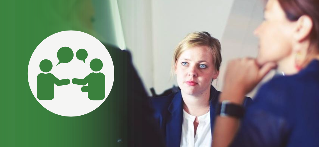 A businesswoman listens attentively in a meeting while another person speaks. A green overlay on the left features an icon of two people in conversation with dialogue bubbles between them, symbolizing communication and conflict resolution.