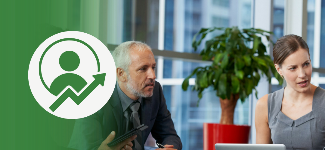 A senior business leader and a younger colleague sit at a modern conference table, engaged in a serious discussion. On the left, a circular icon with a silhouette and upward arrow represents personal or professional growth, set against a green background.